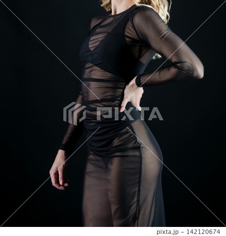 Dancer wearing transparent black dress posing on black background 142120674
