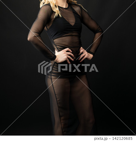 Dancer wearing transparent black dress posing on black background Dancer wearing transparent black dress posing on black background 142120685