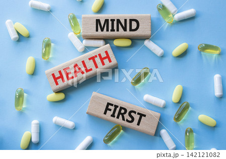 Mind Health First symbol. Concept words Mind Health First on wooden blocks. Beautiful blue background with pills. Healthcare and Mind Health First concept. Copy space. 142121082