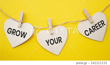 Grow Your Career text on wooden heart tags hanging on rope with clothespins over yellow background. Professional advancement and career growth concept with copy space. Grow Your Career text on wooden heart tags hanging on rope with clothespins over yellow background. Professional advancement and career growth concept with copy space. 142121152