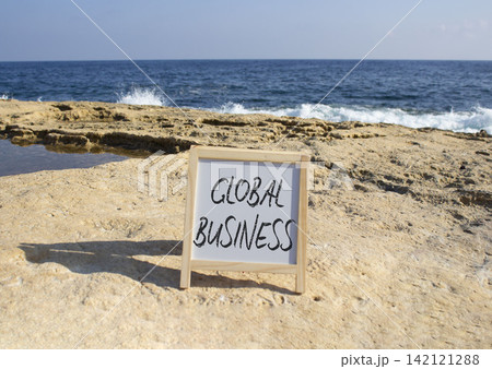 Global Business symbol. White blackboard with Concept words Global Business. Beautiful sea background. Business and Global Business concept. Copy space. Global Business symbol. White blackboard with Concept words Global Business. Beautiful sea background. Business and Global Business concept. Copy space. 142121288