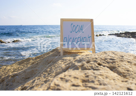 Social Engagement symbol. White blackboard with Concept words Social Engagement. Beautiful sea background. Business and Social Engagement concept. Copy space. 142121612