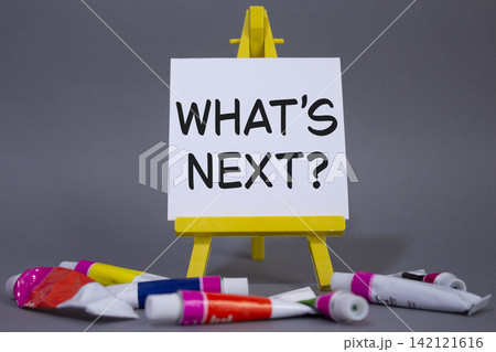 What is next symbol. Concept words What is next on wooden blocks. Beautiful grey background with paints and easel. Business and What is next concept. Copy space. 142121616