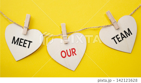 Meet Our Team text on wooden heart tags hanging on rope with clothespins over yellow background. Team introduction and corporate culture concept with copy space. Meet Our Team text on wooden heart tags hanging on rope with clothespins over yellow background. Team introduction and corporate culture concept with copy space. 142121628