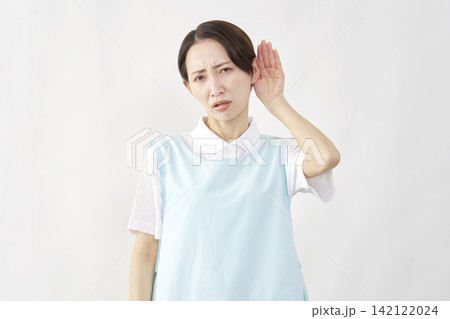 耳に手を当てる介護士女性　白背景 142122024