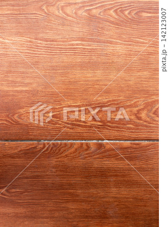 Close up macro view of warm brown wood-look floor tile with realistic natural grain, layered tonal variation and subtle horizontal seam. Rustic material background suitable for flooring, renovation 142123007