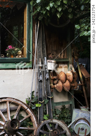 Austrian rustic barn wall with vintage wooden skis and a wagon wheel leaning illustrating a cozy countryside atmosphere. 142123754