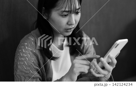 スマホとネガティブな女性イメージ 白黒 スマホとネガティブな女性イメージ 白黒 142124234