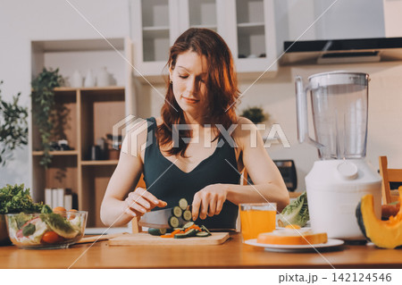 Woman preparing green smoothie in bright kitchen with fresh fruits and vegetables, healthy eating lifestyle moment in natural daylight Woman preparing green smoothie in bright kitchen with fresh fruits and vegetables, healthy eating lifestyle moment in natural daylight 142124546