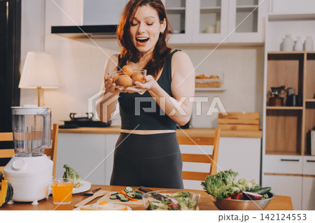 Woman preparing green smoothie in bright kitchen with fresh fruits and vegetables, healthy eating lifestyle moment in natural daylight Woman preparing green smoothie in bright kitchen with fresh fruits and vegetables, healthy eating lifestyle moment in natural daylight 142124553