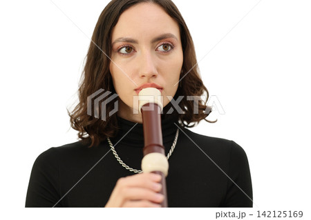 Young woman playing recorder flute in close studio portrait against clean white background, dark hair, black top, silver necklace, focused expression and minimal light Young woman playing recorder flute in close studio portrait against clean white background, dark hair, black top, silver necklace, focused expression and minimal light 142125169