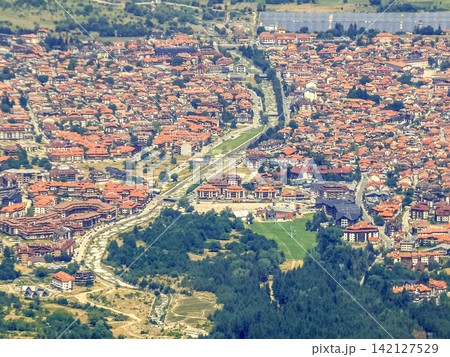 Bansko Bulgaria high angle view of mountain resort town with red tile roofs and Glazne river Bansko Bulgaria high angle view of mountain resort town with red tile roofs and Glazne river 142127529