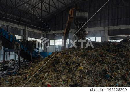 Industrial conveyor belt unloading processed organic waste pile in recycling power plant warehouse. Industrial conveyor belt unloading processed organic waste pile in recycling power plant warehouse. 142128269