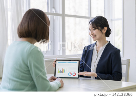 タブレットを使って顧客のミドルシニア世代の女性に説明をする営業ウーマン 142128366