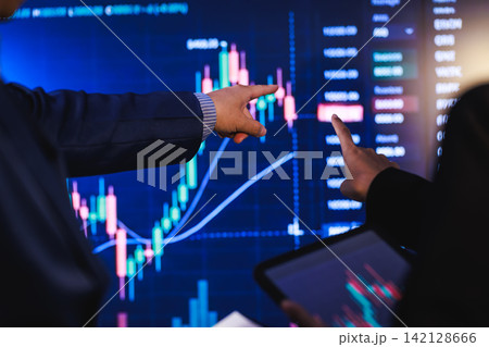 Business people pointing at a stock market chart on a digital screen during a financial analysis meeting Business people pointing at a stock market chart on a digital screen during a financial analysis meeting 142128666