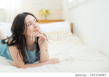 ベッドに座る笑顔の女性 ベッドに座る笑顔の女性 142129067