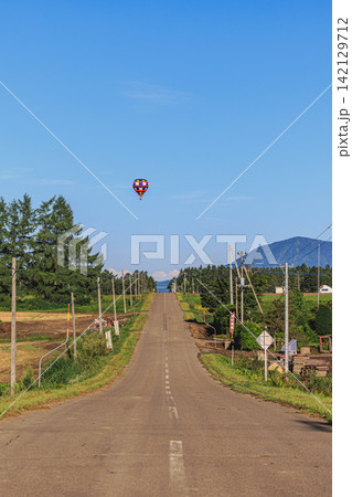 北海道上士幌町のまっすぐに続く一本道と大空をゆったりと散歩するように飛翔する熱気球 北海道上士幌町のまっすぐに続く一本道と大空をゆったりと散歩するように飛翔する熱気球 142129712