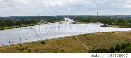 Cargo barge navigates broad Mittellandkanal near Magdeburg, surrounded by green countryside and canal infrastructure. Aerial view shows inland shipping, vessels, waterways and distant wind turbines Cargo barge navigates broad Mittellandkanal near Magdeburg, surrounded by green countryside and canal infrastructure. Aerial view shows inland shipping, vessels, waterways and distant wind turbines 142130667