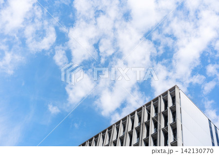 Low angle view of modern concrete office building facade with geometric pattern under cloudy sky in Fukuoka, Japan Low angle view of modern concrete office building facade with geometric pattern under cloudy sky in Fukuoka, Japan 142130770