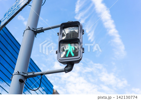 Low angle close-up of pedestrian traffic signal showing green light with copy space against blue sky in Japan Low angle close-up of pedestrian traffic signal showing green light with copy space against blue sky in Japan 142130774