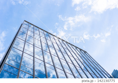 Low angle view of modern glass office building facade reflecting cloudy sky in Fukuoka, Japan Low angle view of modern glass office building facade reflecting cloudy sky in Fukuoka, Japan 142130775