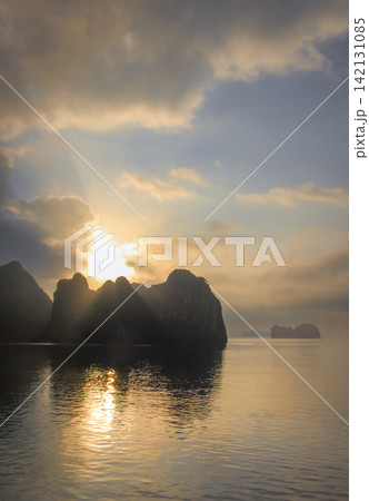 Early morning sun over Halong Bay in Vietnam where small islands rise from the water. Sunrise view with pretty clouds. 142131085
