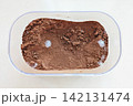 Raw cocoa powder with visible white mold spots inside storage container, showing spoiled food linked to improper storage and expired shelf life 142131474