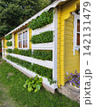 Green herbs growing in long wall planters on yellow wooden house facade, practical vertical gardening with efficient use of exterior space 142131479