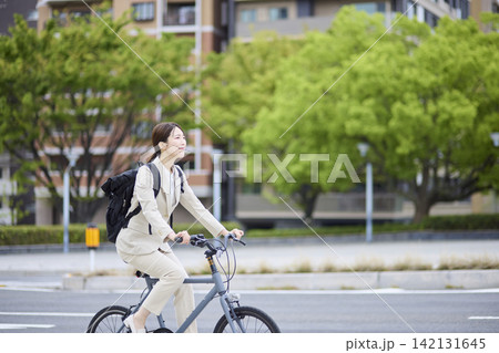 道路を自転車で移動する働く女性 道路を自転車で移動する働く女性 142131645