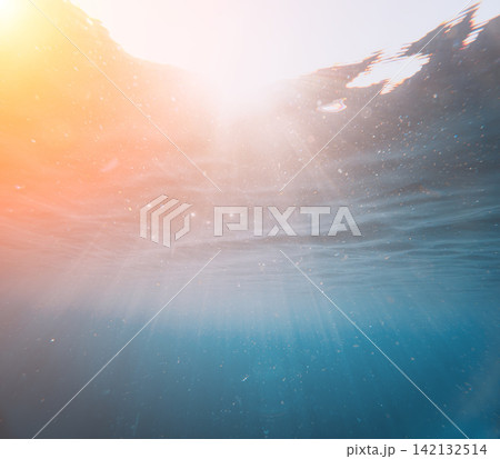 Sunlight breaking through clear blue ocean water with floating particles illuminating the depths Sunlight breaking through clear blue ocean water with floating particles illuminating the depths 142132514