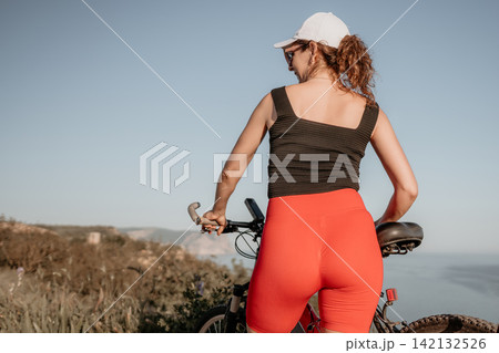 Bicycle, woman, mountains, active young woman standing with bike on a mountain trail overlooking the ocean during a sunny summer day Bicycle, woman, mountains, active young woman standing with bike on a mountain trail overlooking the ocean during a sunny summer day 142132526