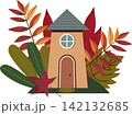 A cozy vector illustration of a tall fairytale house with beige walls, an arched door, and a round window under a gray roof. The building is surrounded by a composition of colorful autumn leaves, bran 142132685
