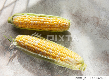 Fresh corn cobs on concrete background Fresh corn cobs on concrete background 142132692