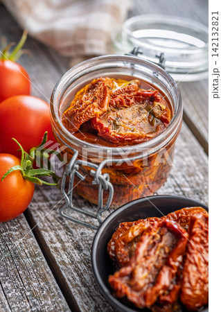 Jar of Sun-Dried Tomatoes in Olive Oil on Rustic Wooden Table with Fresh Tomatoes Jar of Sun-Dried Tomatoes in Olive Oil on Rustic Wooden Table with Fresh Tomatoes 142132821