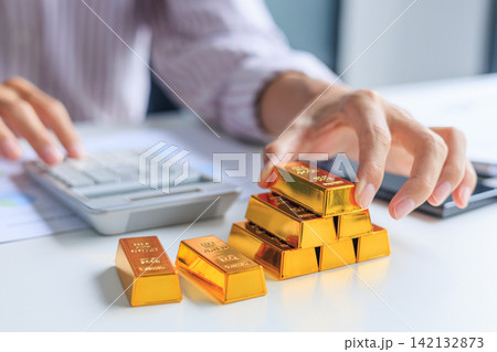 Investor Hands Stacking Counting Gold Bullion Bars on Desk while Calculating Profit. Secure Financial Investment and Wealth Preservation Concept. 142132873