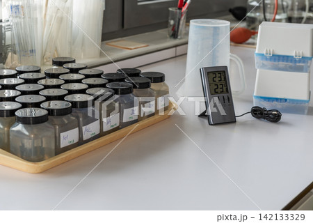 labeled water sample bottles, digital thermometer, plastic boxes on table in laboratory labeled water sample bottles, digital thermometer, plastic boxes on table in laboratory 142133329