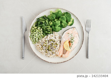 Balanced healthy meal with baked salmon with brown rice and vegetables 142133404