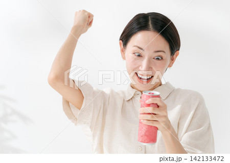 ガッツポーズをしてドリンクを飲む女性 142133472