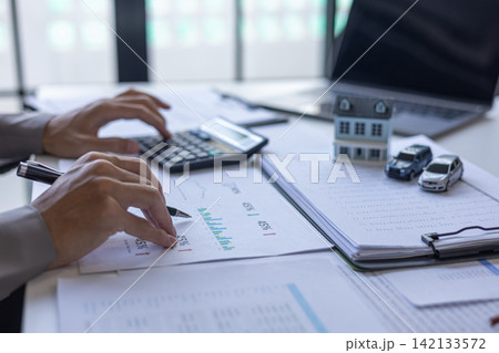 Businessman reviewing financial documents for property investment and auto finance. Businessman reviewing financial documents for property investment and auto finance. 142133572