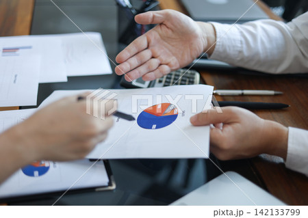 Business professionals reviewing financial documents contain data of pie charts and graphs. 142133799