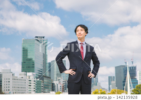 スーツを着た笑顔の若い男性 オフィス街イメージ スーツを着た笑顔の若い男性 オフィス街イメージ 142135928