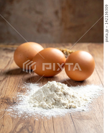 white flour on a wooden surface with fresh brown eggs white flour on a wooden surface with fresh brown eggs 142136309
