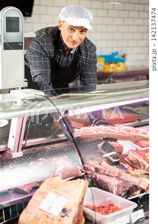 Confident male butcher showing a big piece of beef ribs in butchery Confident male butcher showing a big piece of beef ribs in butchery 142137474