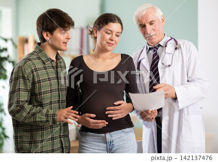 Happy young couple listening elderly doctor's advises about good pregnancy 142137476