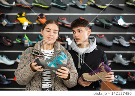 Couple examine view several item of winter comfortable trecking shoes Couple examine view several item of winter comfortable trecking shoes 142137480