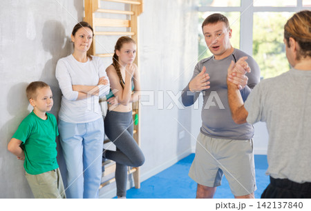 Man coach shows family students technique of performing painful modus with help of wringing hand Man coach shows family students technique of performing painful modus with help of wringing hand 142137840