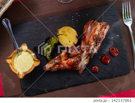 Roast rabbit served with potatoes and braised peppers 142137861