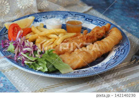 Fish and chips served with salad and sauces on a plate Fish and chips served with salad and sauces on a plate 142140230