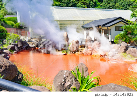 蒸気が立ち上る赤い温泉池と火山岩の風景 142142922