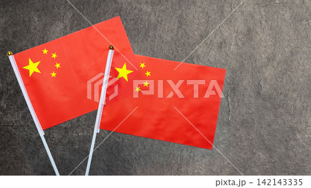 Two small flags of the People's Republic of China on a dark gray textured stone background with copy space. China National Day celebration 142143335